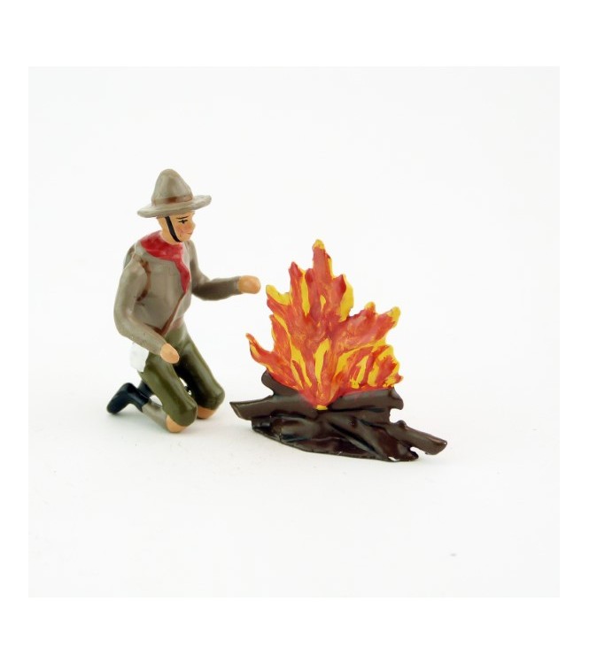 scout à genoux devant un feu de bois