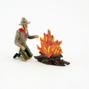 scout à genoux devant un feu de bois