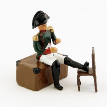 Napoléon assis sur un coffre, pied posé sur une chaise