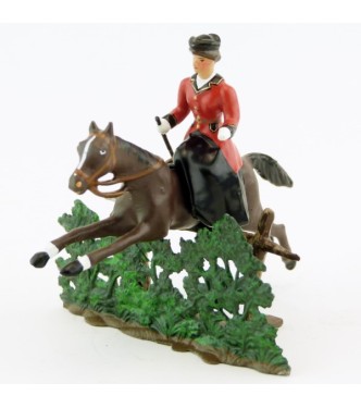 cavalière en amazone sur cheval marron (bai) sautant haie + barrière