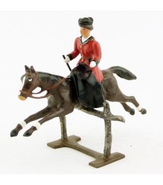 cavalière en amazone sur cheval marron (bai) sautant barrière